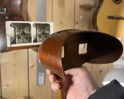 Looking at a 3D photo viewer, with a photo in the clamp. On an angle. It's a device that looks like a mask with a beak, and a double photo standing on the beak. 