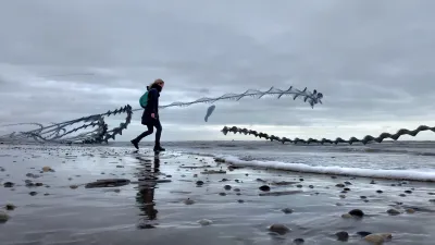 Ryan at the beach. A low wave is just coming in. She walks backwards, this is no trail, just a still. The very low stand point make the shells in the sand big. Dark trails of seaguls and of a kit make this image remarkable. One trail on the right side compliments the foam on the incoming wave.