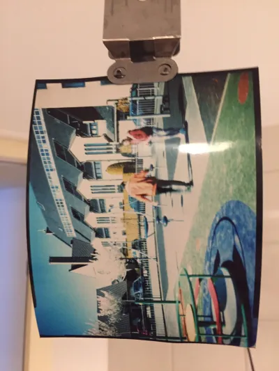 Photo hanging to dry, on it’s side. Two guys in their thirties playing with a ball in a children’s playground. Bright green and red playing attributes and a church  behind them.