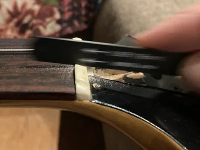 Looking at the top of the neck. There is movement blur of my hand filing. Now the frets are gone, the strings need to sit lower.