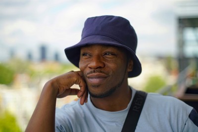Photo of a guy with a blue hat, in front of a blurry background. This background expresses our conversation to a certain extend. 