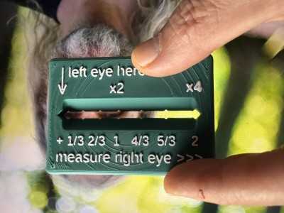 A little green plastic ruler with white numbers on it, is held up against the ground glass, to show how it measures eye distance. Embarrasingly, my flow rate compensation was way off during the printing of this ruler.